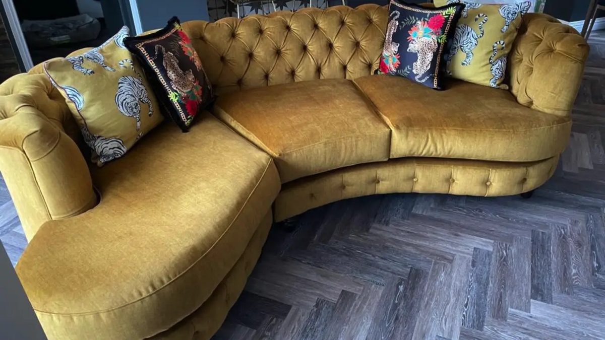 Curved sofa reupholstered in mustard velvet with patterned scatter cushions
